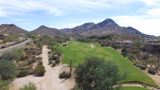 Beautiful golf course from above with irrigation sprinkler watering grass