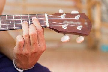 Close up playing ukulele , touch chord ,string instrument  , body part