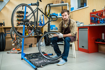 Confident master of bicycle repair sitting by bike with open toolbox