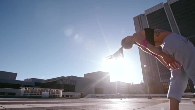 Woman doing frontflip outdoors in city. Urban female in action practicing parkour and flashkick.