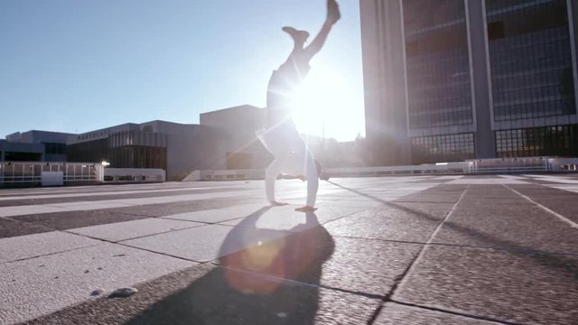 Parkour man jumping high and performing a back flip in urban space. Urban man practicing parkour outdoors in city.