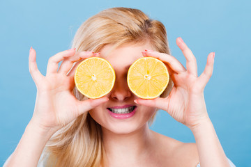 Woman holding fruit lemon half on eyes