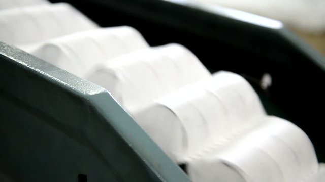 plant for making mattresses Machine transports a block of independent springs packed in a sheath. On conveyor are moving white ribbons with metal rods for orthopedic mattress.
