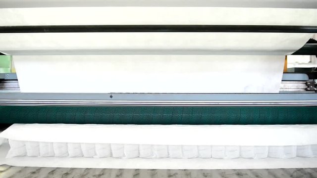 White fabric for mattress on machine in workshop in factory. Knitted textile for orthopedic mattresses is one of best types of tissues, canvas perfectly sits on product, repeating all its bends.