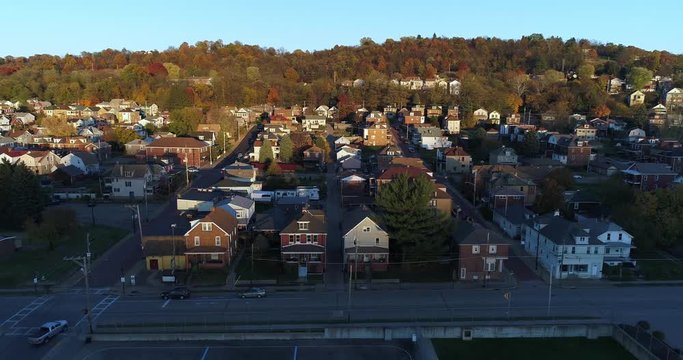 A wide profile moving aerial establishing shot of a typical Pennsylvania small town at sunset. Pittsburgh suburbs.  	