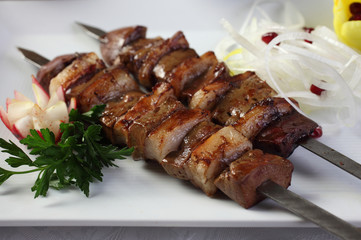 Kebab of lamb liver with sheep's tail fat.Salt and spices to taste.To the table served with chopped onions and herbs garnished with pomegranate seeds.Uzbek cuisine.