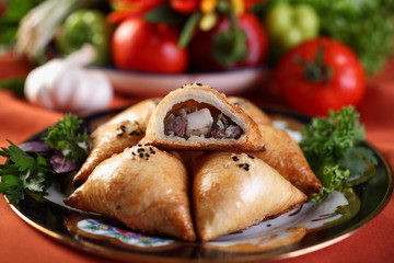 Samsa are triangular in shape with a lamb and a big piece of sheep fat.The puff pastry on top sprinkled with Nigella.Bake in the tandoor.Uzbek cuisine.