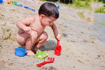 Little latin boy playing with sand on the beach.