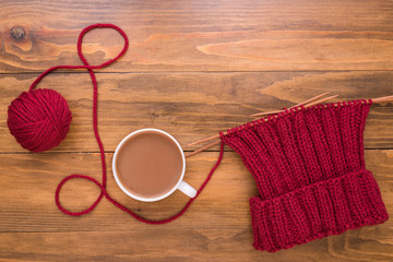 Coffee and red knitting on wooden background