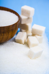 Sugar in a wooden bowl and cubes of sugar
