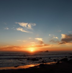 Fototapeta na wymiar sun goes down the skyline on the ocean with small island silhouette
