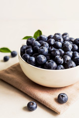 Juicy and fresh blueberries with green leaves on white bowl. Healthy eating