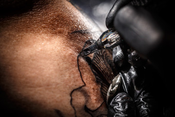 Artist tattooing of man's skin