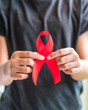 Aids red ribbon on girl teenager&rsquo;s hand support for World aids day and national HIV/AIDS awareness month campaign concept