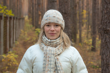 Portrait of a young pretty woman in winter clothes on a background of autumnal scenery