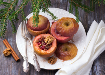 Baked apples stuffed with cranberries, walnuts and honey with cinnamon on a white plate on a wooden table, selective focus. Delicious healthy vegan dessert