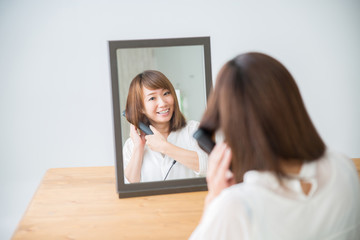 ヘアアイロンを使う女性（笑顔）

