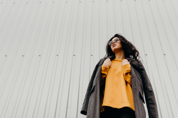 Portrait of stylish modern young curly woman in coat sunglasses