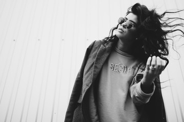 Portrait of stylish modern young curly woman in coat sunglasses
