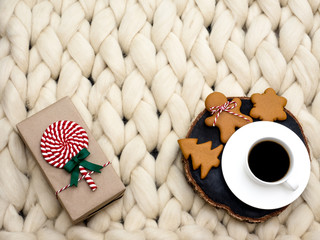 Cozy composition, closeup merino wool blanket, warm and comfortable atmosphere. Knit background. Cup of coffee and ginger cookies. Christmas concept.