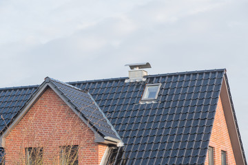 Modernes Dach mit Schornstein und schwarzen Dachpfannen