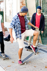 Teenage friends walking at the street with skateboards