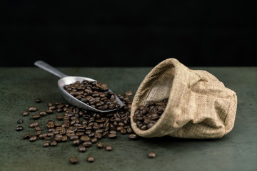 Close up of roast coffee beans in the scoop with bag on the stone table background
