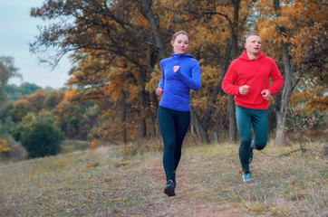 Coupe of jogger fast run along the path on the colorful  autumnal forest