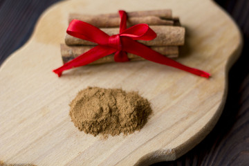 Cinnamon sticks and meal close up on a wooden Board on the table