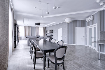 Large dining table in the interior of the apartment in a stylish modern design.