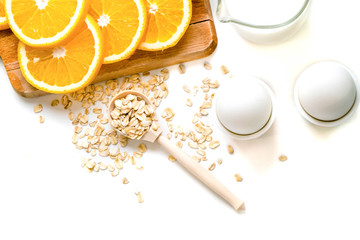 Oat flakes plate with milk, orange, eggs on a wooden white table. Top view of healthy oat flakes breakfast. Copy space. blue napkin Breakfast in bed plate, breakfast table buffet. Healthy ingredients.