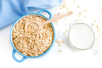 Oat flakes plate with milk, orange, eggs on a wooden white table. Top view of healthy oat flakes breakfast. Copy space. blue napkin Breakfast in bed plate, breakfast table buffet. Healthy ingredients.