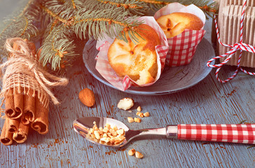 Lemon muffins on rustic wooden table with Christmas twigs, almonds and cinnamon sticks