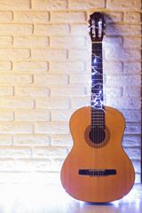 Fototapeta na wymiar Guitar with lighted garlands on white brick background