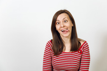 Beautiful European young happy brown-haired woman with healthy clean skin, dressed in casual red and grey clothes, fooling and showing the tongue on a white background. Emotions concept.