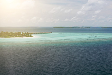 Fototapeta na wymiar Tropical islands and atolls in Maldives in Indian Ocean from aerial view. Piece of paradise on the Earth. Good choice for vacation. Beautiful top view for wallpaper.