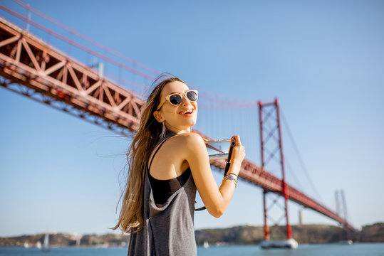 Young woman tourist photographing famous iron bridge in Lisbon city, Portugal