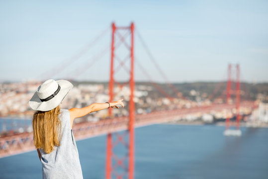 Young woman tourist enjoying beautiful aerial landscape view on the famous iron bridge in Lisbon city, Portugal