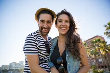 Happy man in hat standing with girlfriend outside laughing