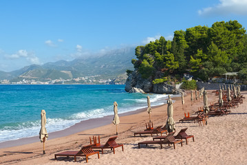 Deserted beach with sunbeds and closed umbrellas