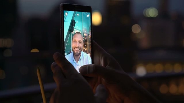 Man with cocktail taking selfie photo with cellphone at night 
