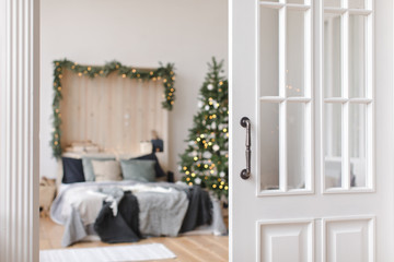 Wooden opened doors showing view of bedroom interior with Christmas tree glowing.