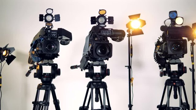Three professional video cameras on tripods. 