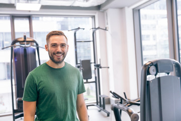 Fototapeta na wymiar Smiling man surrounded by gym equipment.