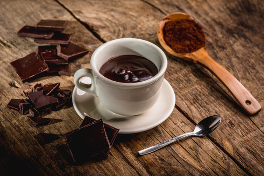 chocolate cup on wooden table with dark chocolate and powder