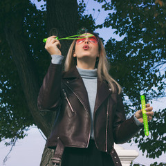 Young pretty girl blows soap bubbles, outdoor  