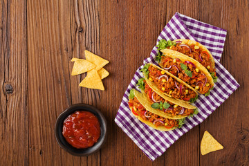 Tacos with meat and vegetables on wooden board