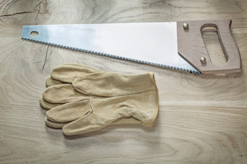 Composition of safety gloves stainless handsaw on wood board con