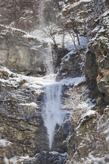 Fototapeta na wymiar snow slide avalanche at rock wall cliff, winter, trees