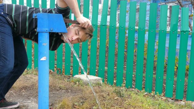 Guy drinks water from the water column